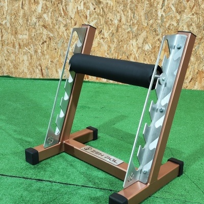 Suporte metálico dourado e prateado para barra de exercício com espuma preta em relva sintética